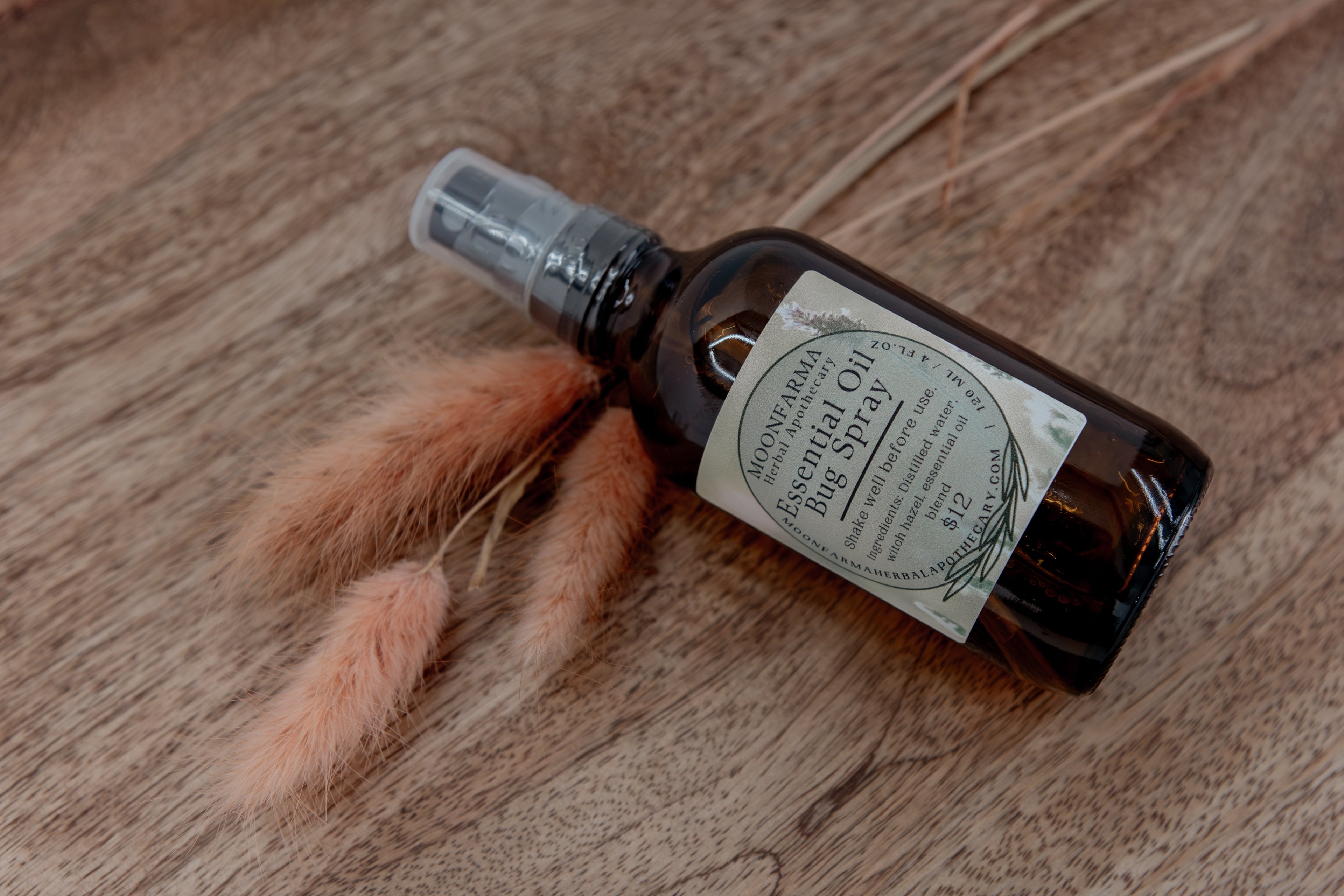 MoonFarma essential oil bug spray bottle with natural ingredients and spray nozzle for outdoor insect repellent.