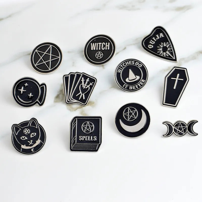 Black and white witchy pins from Green Witch Creations, featuring mystical symbols and intricate designs on metal pins.