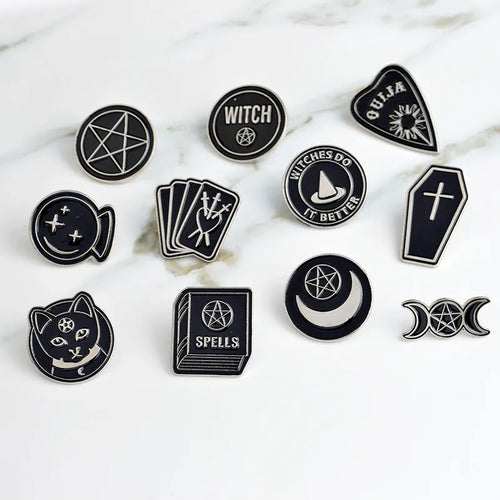 Black and white witchy pins from Green Witch Creations, featuring mystical symbols and intricate designs on metal pins.