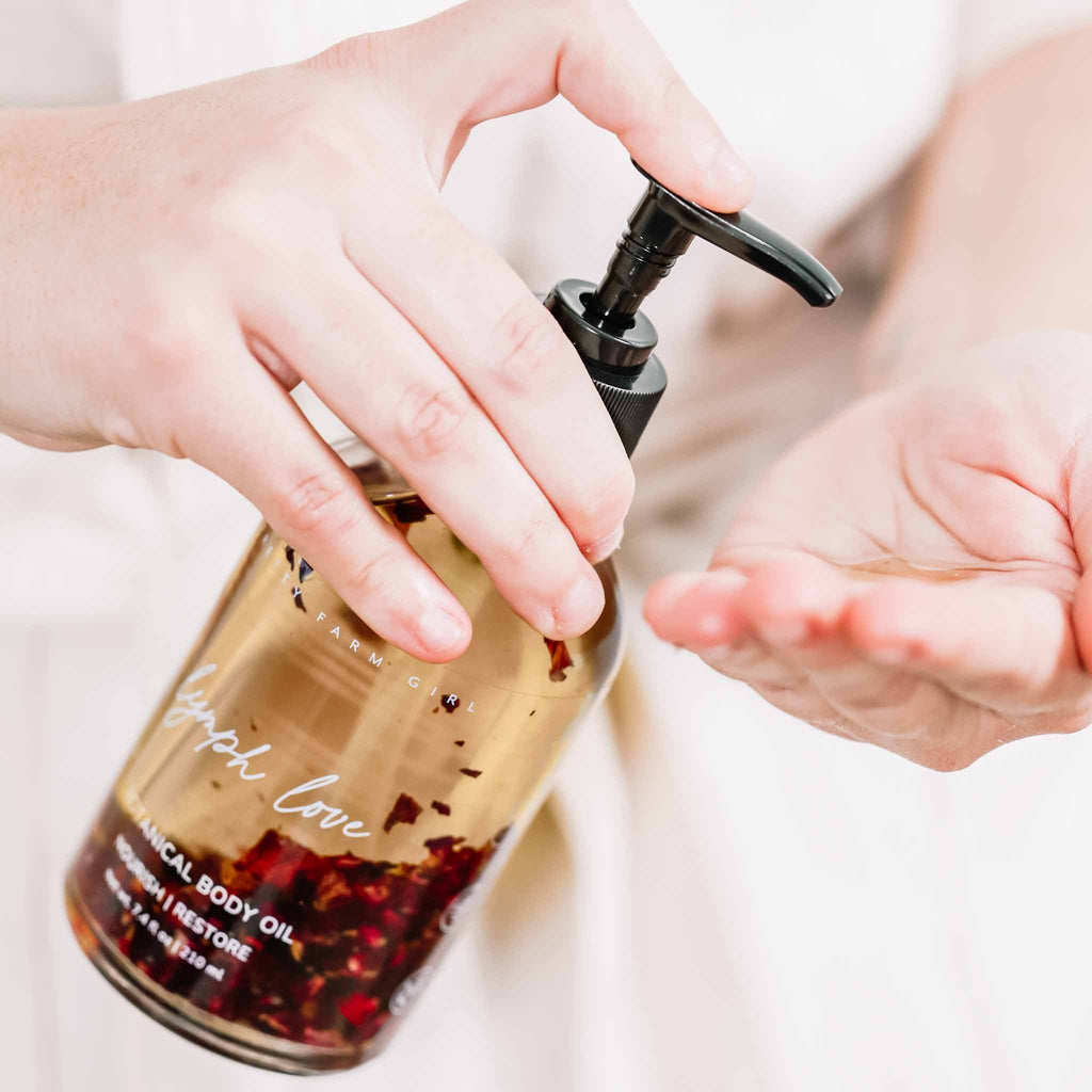 Pretty farm girl Lymph Love natural body oil for lymphatic massages, featuring a bottle of health and beauty product with botanical ingredients.