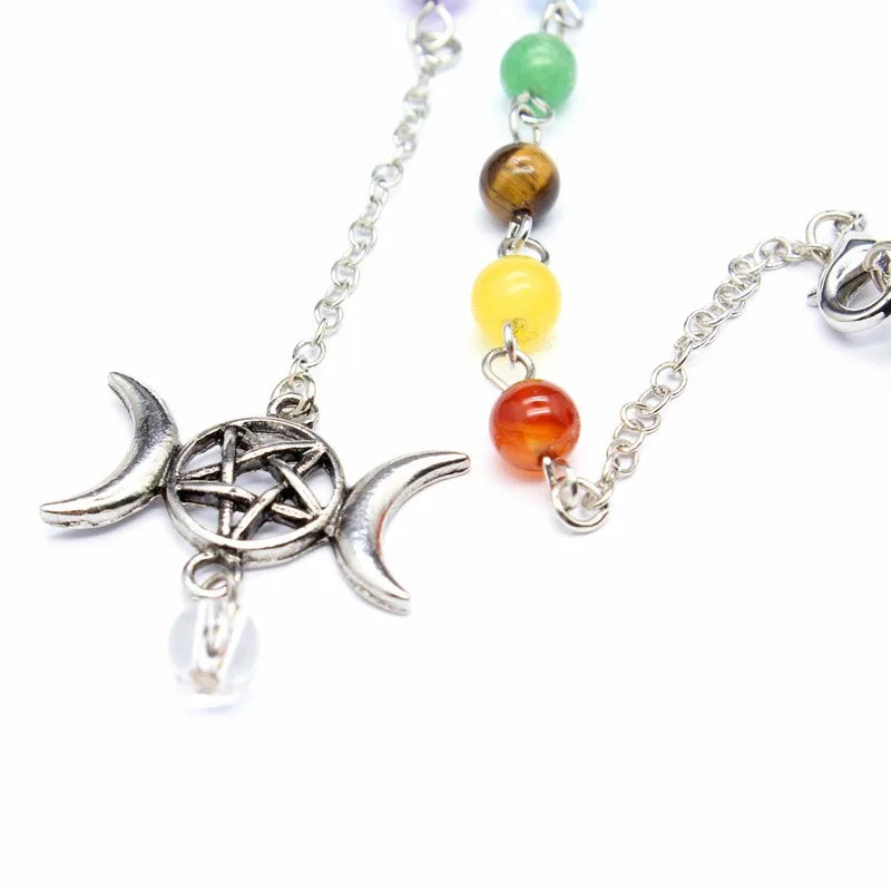 Green Witch Creations Triple Moon Pentacle Chakra Pendulum hanging from a chain with intricate symbols and a crescent moon design.